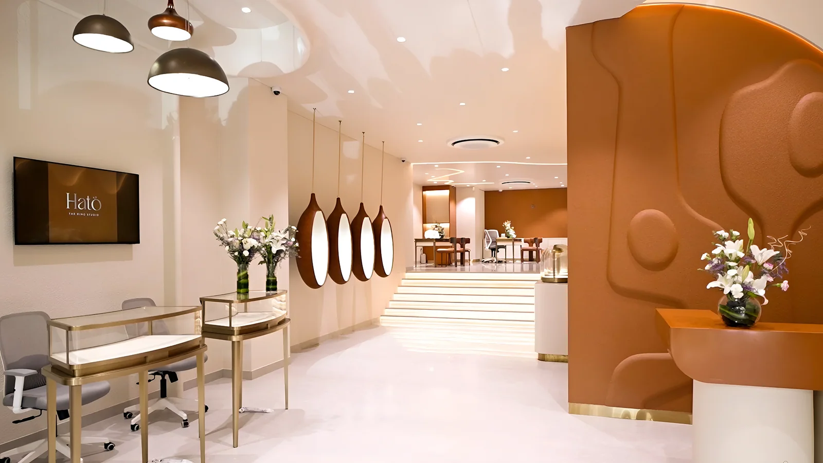 Studio interior: sculpted wall, brass display cases and pendant lights